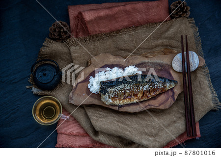 Japanese meal for dinner saba fish grilled on rice with teriyaki sauce on a wooden background served with hot tea. Japanese style. 87801016