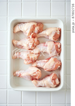調理バットに並べた鶏の手羽元 87802736