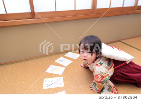 1歳の誕生日に袴を着て一升餅を背負って選び取りをする子供 87802804