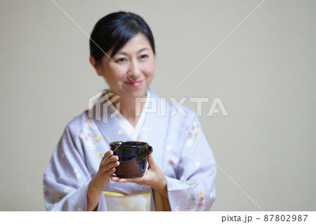 着物姿でお酒を勧める日本人女性　お酒の片口を持つ中年女性 87802987