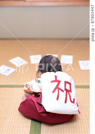 1歳の誕生日に袴を着て一升餅を背負って選び取りをする子供 87803447