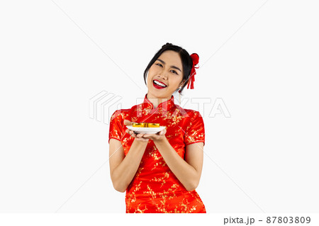 Asian woman in red traditional oriental costume holding plate of teas isolated on white background. Chinese new year concept style.. 87803809