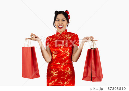 Asian woman in red traditional oriental costume holding shopping bags isolated on white background. Chinese new year in shopping concept style. 87803810