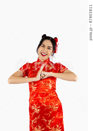 Asian woman in red traditional oriental costume with chinese greeting gestures isolated on white background. Chinese new year concept style.. 87803811