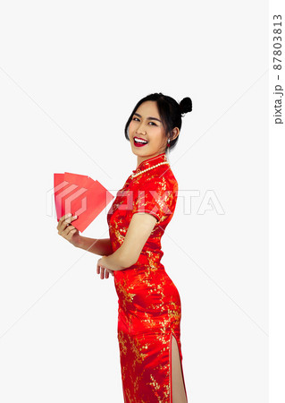 Chinese new year woman concept, isolated asian woman wearing red dress Cheongsam, smiling and holding red envelopes or Ang Pow. 87803813