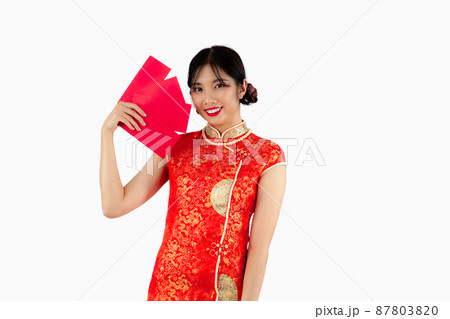 Chinese new year woman concept, Asian woman smiling and holding red envelopes or Ang Pow in red dress Cheongsam. 87803820