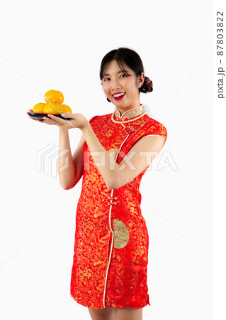 Chinese new year concept style. Happy Asian woman in red Cheongsam dress holding a plate of oranges on white background.. 87803822