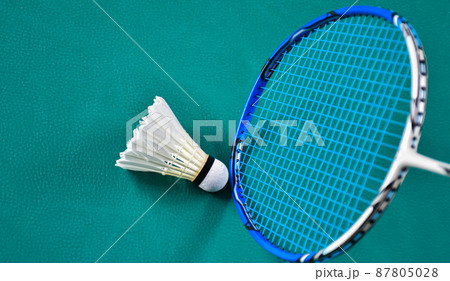 Cream white badminton shuttlecock and rackets on green floor in indoor badminton court, soft and selective focus, copy space, concept for badminton lovers around the world. 87805028