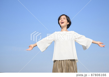 腕を伸ばして深呼吸する女性　青空 87806166