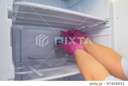 A cleaning lady washes the freezer. Cleaning the refrigerator. Selective focus. 87806641