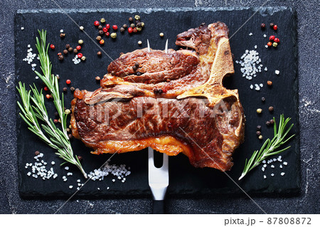porterhouse steak is speared with carving fork 87808872