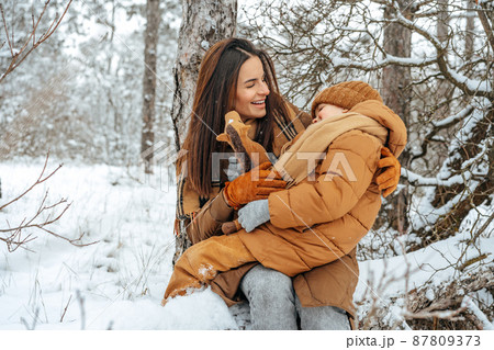 Woman with a little son on a winter hike in the snowy forest Woman with a little son on a winter hike in the snowy forest 87809373