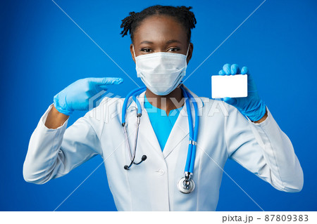 African american doctor woman hold blank empty business card in blue studio African american doctor woman hold blank empty business card in blue studio 87809383