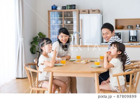 ダイニングでおやつを食べる若い家族 87809899