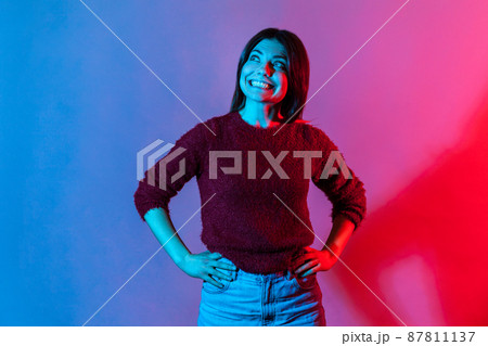 Happy emotions. Neon light portrait of joyful delighted woman in pullover looking up with wide toothy smile, cheerful grinning, laughing after hearing funny joke, anecdote. indoor studio shot isolated Happy emotions. Neon light portrait of joyful delighted woman in pullover looking up with wide toothy smile, cheerful grinning, laughing after hearing funny joke, anecdote. indoor studio shot isolated 87811137