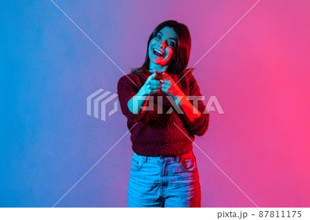 Hey, you are awesome. Neon light portrait of happy optimistic woman pointing direction to camera and smiling broadly, noticing you lucky winner, making choice with finger. indoor studio shot isolated Hey, you are awesome. Neon light portrait of happy optimistic woman pointing direction to camera and smiling broadly, noticing you lucky winner, making choice with finger. indoor studio shot isolated 87811175