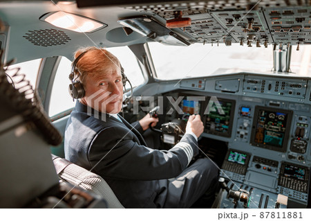 Male pilot in headphones sitting in airplane cockpit 87811881