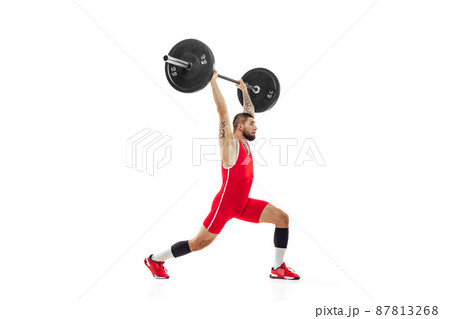 Full length portrait of man in red sportswear exercising with a weight isolated on white background. Sport, weightlifting, power, achievements concept 87813268