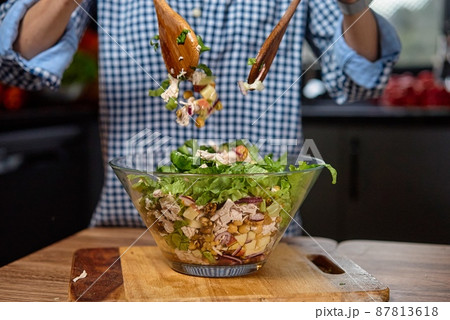 Young woman is preparing vegetable salad in the kitchen. Healthy Food. Vegan Salad. Diet. Dieting Young woman is preparing vegetable salad in the kitchen. Healthy Food. Vegan Salad. Diet. Dieting 87813618
