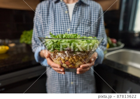 Bowl of fresh green salad in the women's hand. Bowl of fresh green salad in the women's hand. 87813622