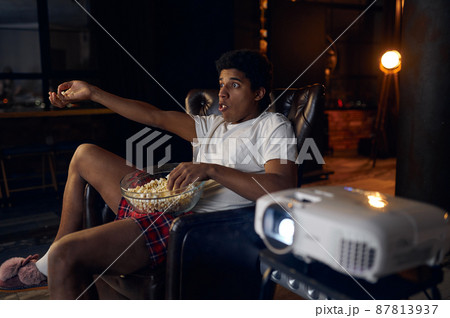 Surprised indignant man watching film on projector Surprised indignant man watching film on projector 87813937