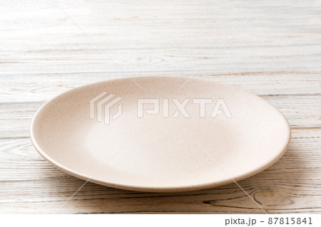 Perspective view of empty light plate on wooden background. Empty space for your design Perspective view of empty light plate on wooden background. Empty space for your design 87815841
