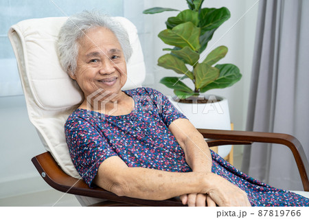 Asian elderly woman sitting and relaxing with happy in rocking chair at room in home. 87819766