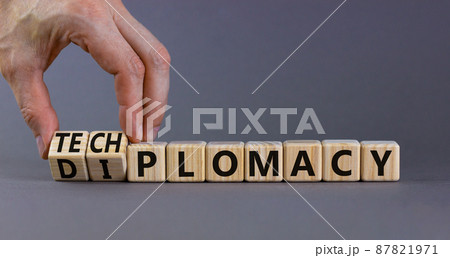 Diplomacy or techplomacy symbol. Businessman turns cubes and changes the concept word diplomacy to techplomacy. Beautiful grey background, copy space. Business, diplomacy or techplomacy concept. 87821971