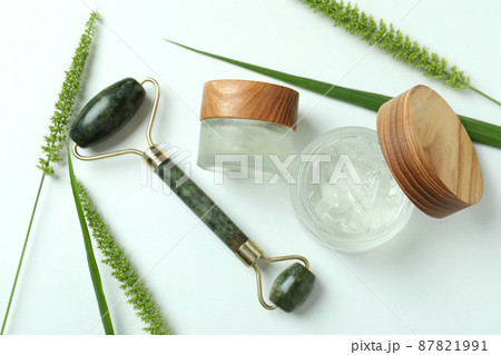 Skin care concept with green face roller on white background Skin care concept with green face roller on white background 87821991