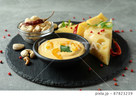 Tray with cheese sauce and ingredients on gray textured table 87823239