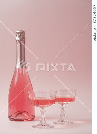 Two crystal glasses and bottle of rose sparkling wine or champagne on pastel pink background. Holiday concept. Minimal creative composition with copy space. 87824057
