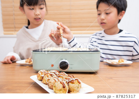 自宅でたこ焼きを焼くアジア人の家族 87825317