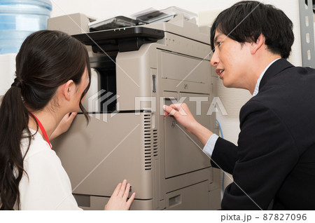 調子の悪いコピー機を直す男性と女性 87827096