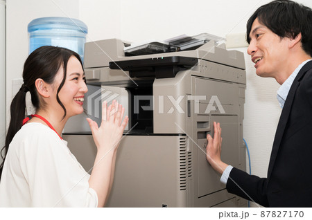 コピー機を直す男性と喜ぶ女性 87827170