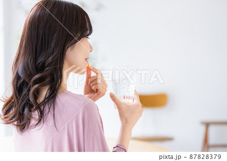 カプセル錠剤を飲む部屋着の女性 87828379