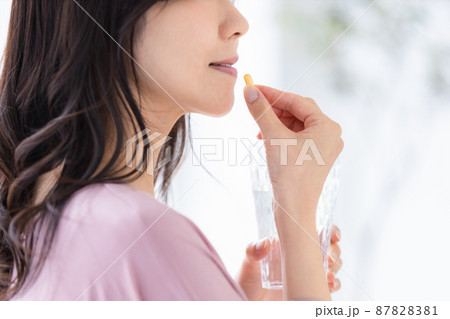 カプセル錠剤を飲む部屋着の女性 87828381