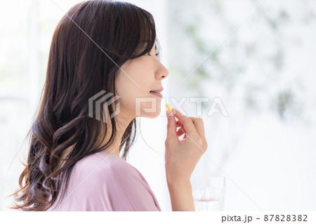 カプセル錠剤を飲む部屋着の女性 87828382