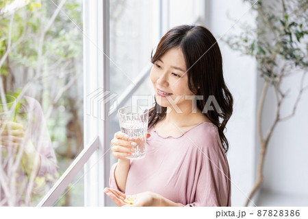 カプセル錠剤を飲む部屋着の女性 87828386