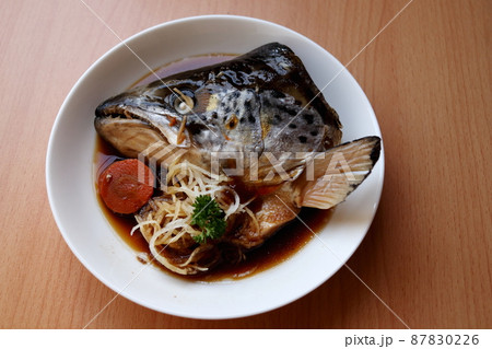 Salmon's head kabutoni on dish and wood background. Salmon's head kabutoni on dish and wood background. 87830226
