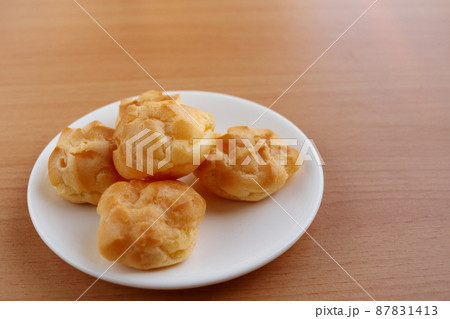 Eclair on white round dish and light brown wood background. 87831413