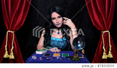 Psychic with Crystal Ball and tarot cards in Red Velvet Tent 87833054