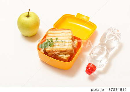 Yellow lunch box with toasted slices of bread, cheese and green parsley. 87834612
