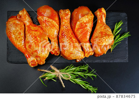 Convenience food, precooked.Raw Marinated chicken meat legs with spices for cooking for BBQ dark background. Top view.Copy space. 87834675