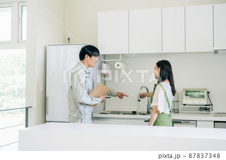 キッチンと作業着姿の男性（水道・笑顔） 87837348