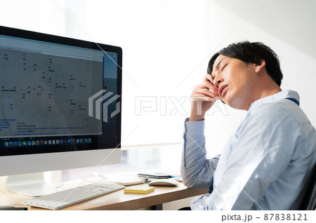 パソコンの前で疲れた表情の男性電気系エンジニア 87838121