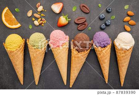 Various of ice cream flavor in cones blueberry ,pistachio ,almond ,orange and chocolate setup on dark stone background . Summer and Sweet menu concept. 87839390