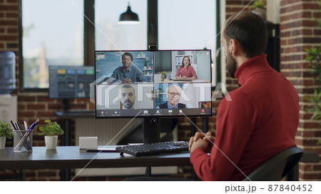 Businessman talking to colleagues on remote videoconference, meeting on online videocall communication with internet connection. Young adult using teleconference at office job. Tripod shot. 87840452