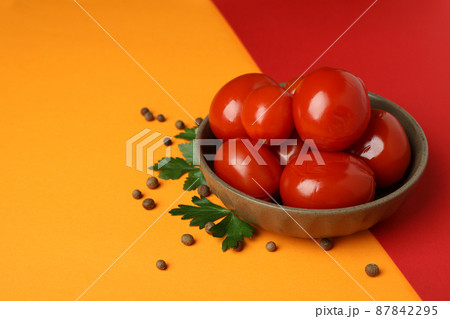Bowl with pickled tomatoes and spices on two tone background Bowl with pickled tomatoes and spices on two tone background 87842295