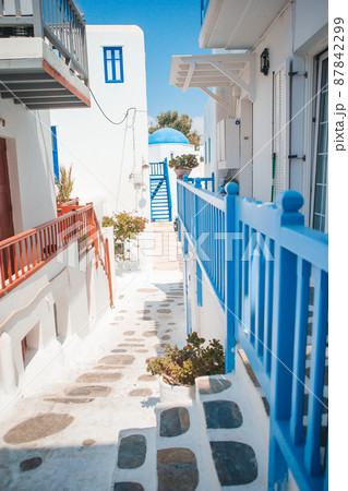 The narrow streets of the island with blue balconies, stairs and flowers in Greece. 87842299