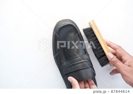 cleaning Shoe with a brush on floor  87844614